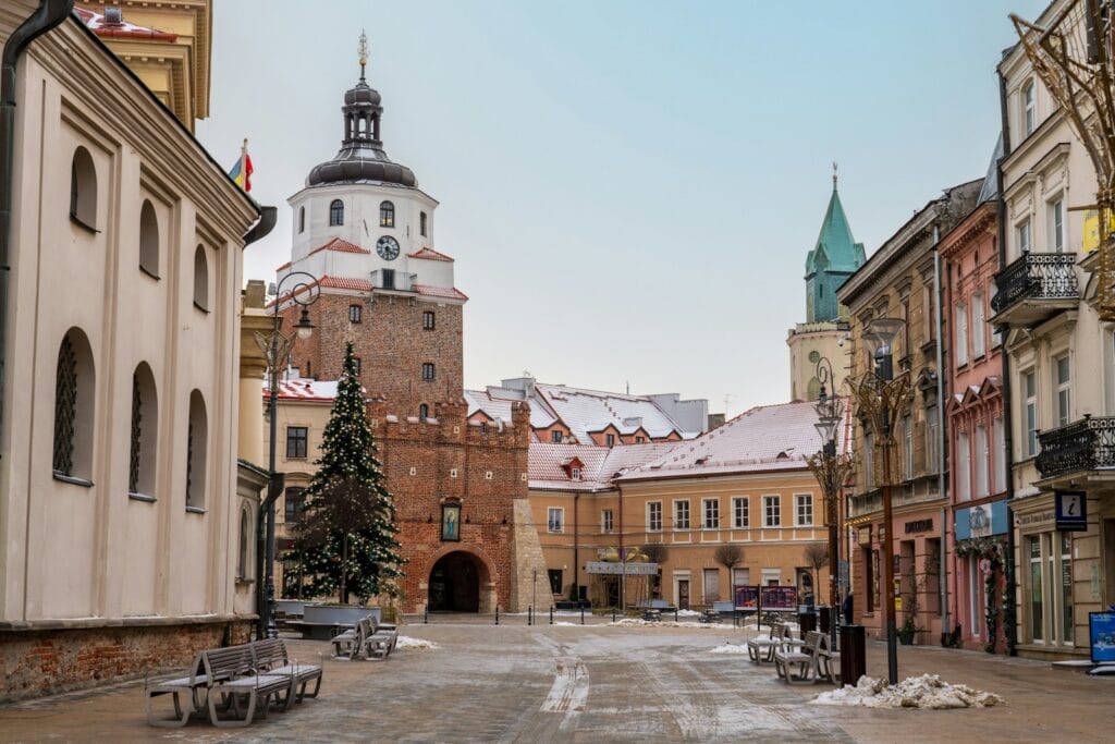 засніжена вулиця з лавками та церквою на задньому плані
